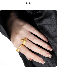 Close-up of golden heart-shaped spiral open ring on a model wearing black silk fabric