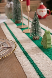 Detail of green and beige striped knitted table runner with thick cable texture and festive decor