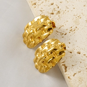 Golden titanium steel stud earrings with woven texture on a beige stone surface