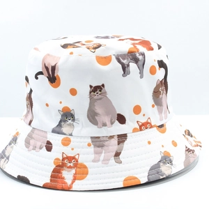 Close-up of white bucket hat featuring cute cartoon cat prints and orange polka dots