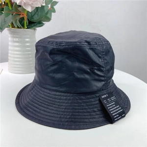 Detail of water-resistant black bucket hat with decorative side label and woven text
