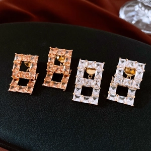 Vue macro de boucles d'oreilles carrées plaquées or avec zircons cubiques champagne et blancs