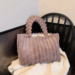 Fuzzy pink plush tote bag with striped texture and spherical handle on a black chair