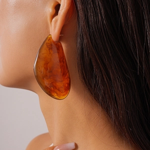 Gros plan sur de grandes boucles d'oreilles irrégulières en résine ambrée translucide