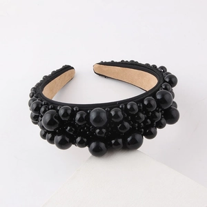 Close-up of black braided headband with large and small glossy pearls on a velvet lining