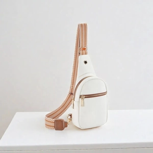 Close-up of white canvas crossbody bag with brown woven strap and gold zipper details