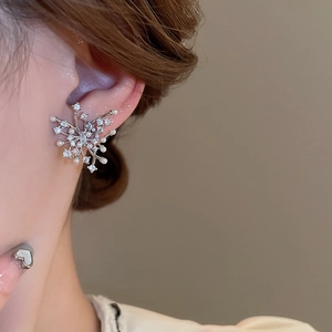 Close-up of irregular silver zircon and pearl firework studs worn on the earlobe