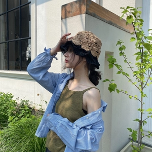 Detail of straw bucket hat with black ruffle edge and crochet texture on a female model