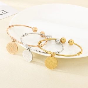 Three colors of stainless steel open bangles with cross charms in gold, silver, and rose gold