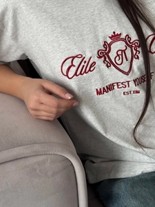 Gros plan de la broderie couronne rouge et texte Elite sur un t-shirt en coton gris