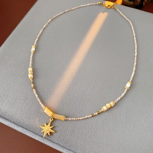 Detail of star pendant on freshwater pearl necklace with gold spacer beads on velvet