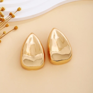 Macro detail of polished gold teardrop stud earrings with smooth metallic mirror finish