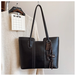 Detail of black tote bag with white contrast stitching and cute cat bag charms
