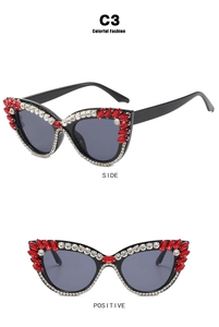 Detail view showing black cat eye sunglasses with intricate red and white rhinestone inlay
