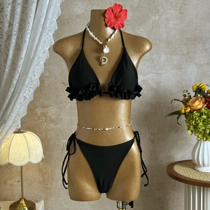 Close-up of black ruffle bikini set with halter top and side-tie bottoms on mannequin