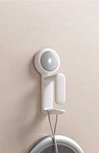 Macro shot of a white wall-mounted suction hook holding a washbasin on damp tiles
