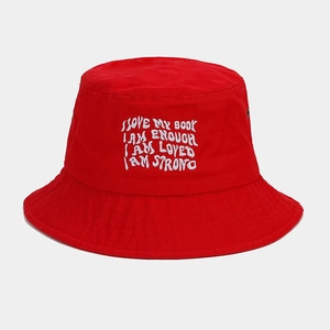 Détail d'un bob en toile rouge avec slogans brodés en blanc et œillets d'aération en métal