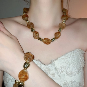 Close-up of amber acrylic beads and gold metal spacers on a necklace and bracelet set