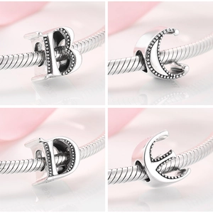 Macro detail of S925 silver alphabet charms B, C, D, E with beaded texture for bracelets