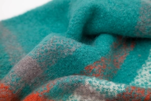 Macro shot of plaid knit fabric with blue, grey and orange stripes and wool texture