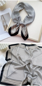 Détail d'un foulard carré en soie à rayures noires et blanches noué en un nœud élégant