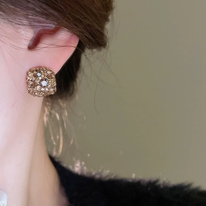 Close-up of elegant square gold plated diamond earrings worn on a model side profile