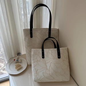 Detail of French vintage canvas tote bag with leaf embroidery and black leather handles