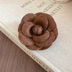 Close-up of a brown fabric camellia brooch on a book with elegant artistic texture