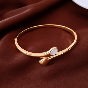 Detail of gold-plated oval cross-clasp bracelet with white teardrop cabochon on silk
