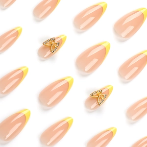 French almond press-on nails in nude and yellow with 3D rhinestone butterfly accents
