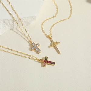 Three 14K gold plated cross necklaces with sparkling zircon inlay on white rock background