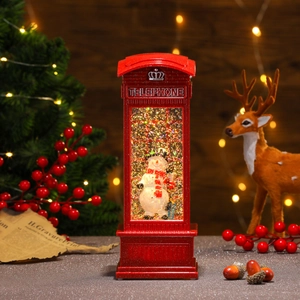 Close-up of a lit red Christmas telephone booth lamp featuring a snowman inside