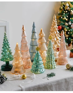 Close-up of colorful ribbed glass Christmas trees with warm LED lights and pine cones