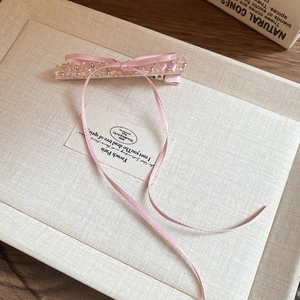 Detailed view of pink ribbon bow hair clip with crystal beads and silver duckbill clip