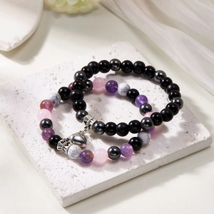 Close-up of magnetic heart couples bracelets featuring natural stone beads on a stone base