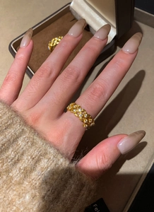 Close-up of gold plated hollow crisscross ring with zircons worn on index finger