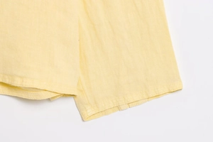 Detailed macro view of high-quality hem stitching on bright yellow linen fabric shirt