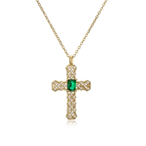 Gold cross necklace with green gemstone and sparkling zircons on white background