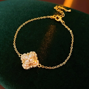 Détail d'un bracelet trèfle avec perle centrale et zircons sur velours vert foncé