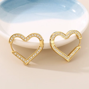 Detail of gold heart hoop earrings with sparkling cubic zirconia on a ceramic tray