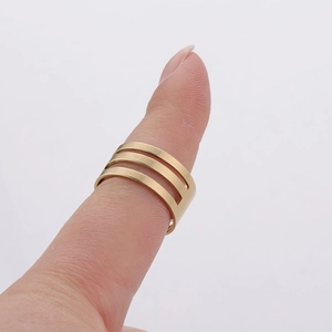 Detailed view of a three-row golden minimalist open ring accessory worn on a finger