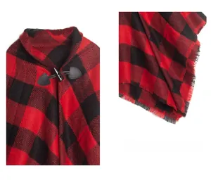 Detail of red buffalo plaid poncho featuring a black horn button and leather strap buckle