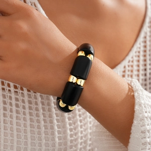Detail of ethnic acrylic oval link bracelet with matte black and gold beads on wrist