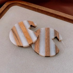 Detailed view of round wood and resin earrings on a soft grey jewelry tray