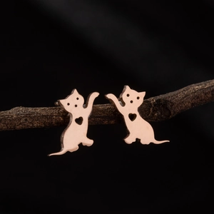 Détail de boucles d'oreilles chat en or rose avec motif cœur sur une branche naturelle