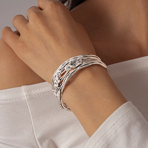 Close-up of silver multilayered open cuff bracelet with detailed floral and leaf relief
