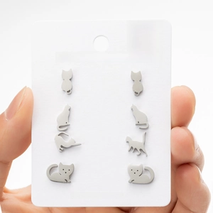 Detail view of four pairs of asymmetric stainless steel cat stud earrings on a white card