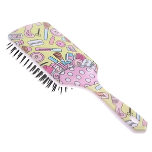 Detail of yellow paddle brush featuring colorful cartoon cosmetics print and air cushion