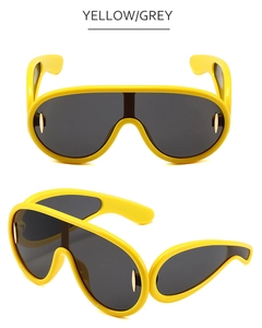 Detail view of yellow oversized wrap sunglasses with grey lenses and gold oval accents