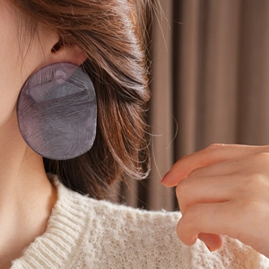 Macro view of large irregular oval resin earrings with deep purple textured finish